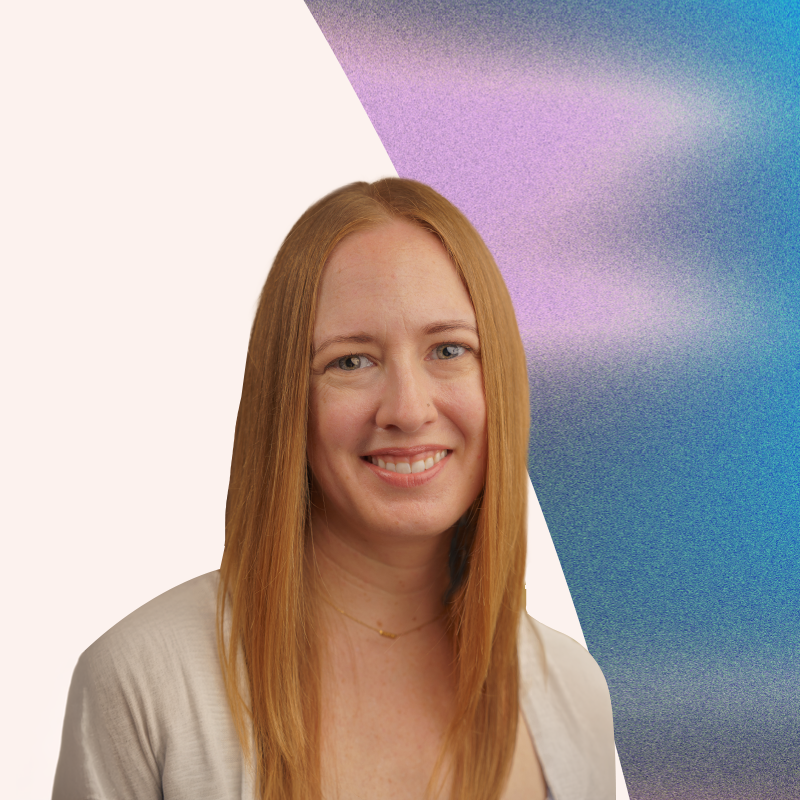 Lydia Storie - Head of Content, Give Not Take Media - A woman with long red hair smiling, wearing a light-colored top and a delicate necklace, standing outdoors with a sky and purple-tinted background.