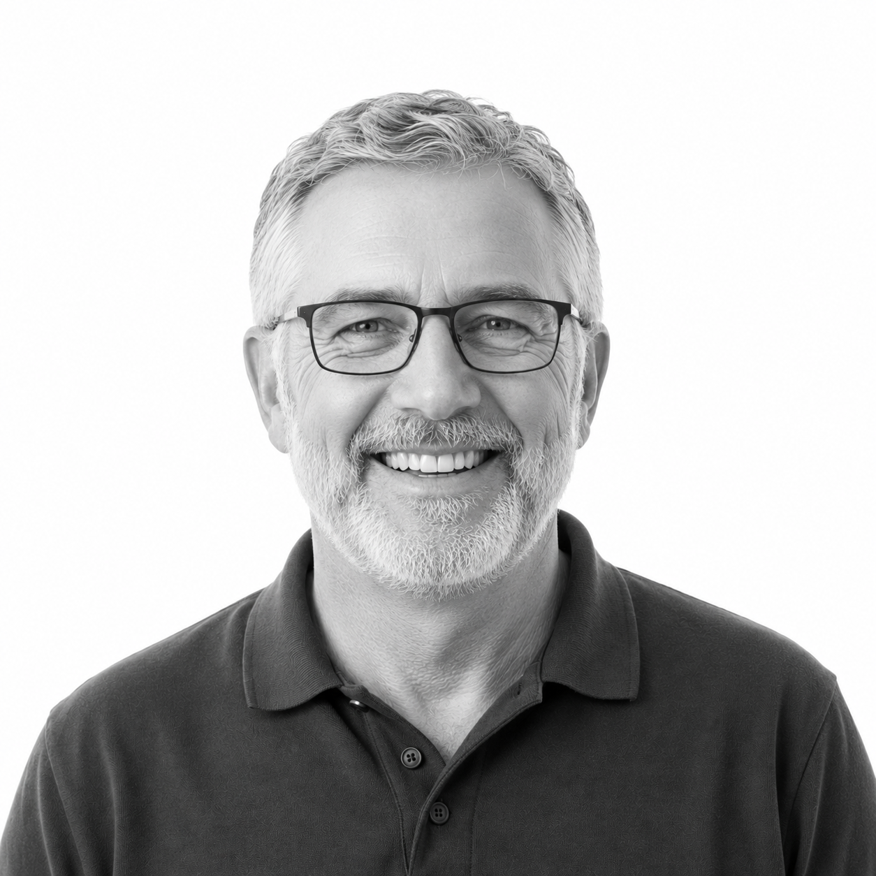 Black and white portrait of smiling middle-aged man with glasses and a beard, wearing a polo shirt.