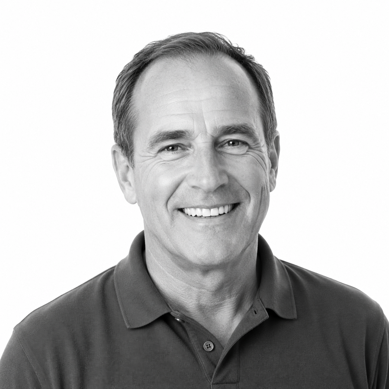 Black and white portrait of a smiling middle-aged man with short hair wearing a polo shirt, against a plain background.