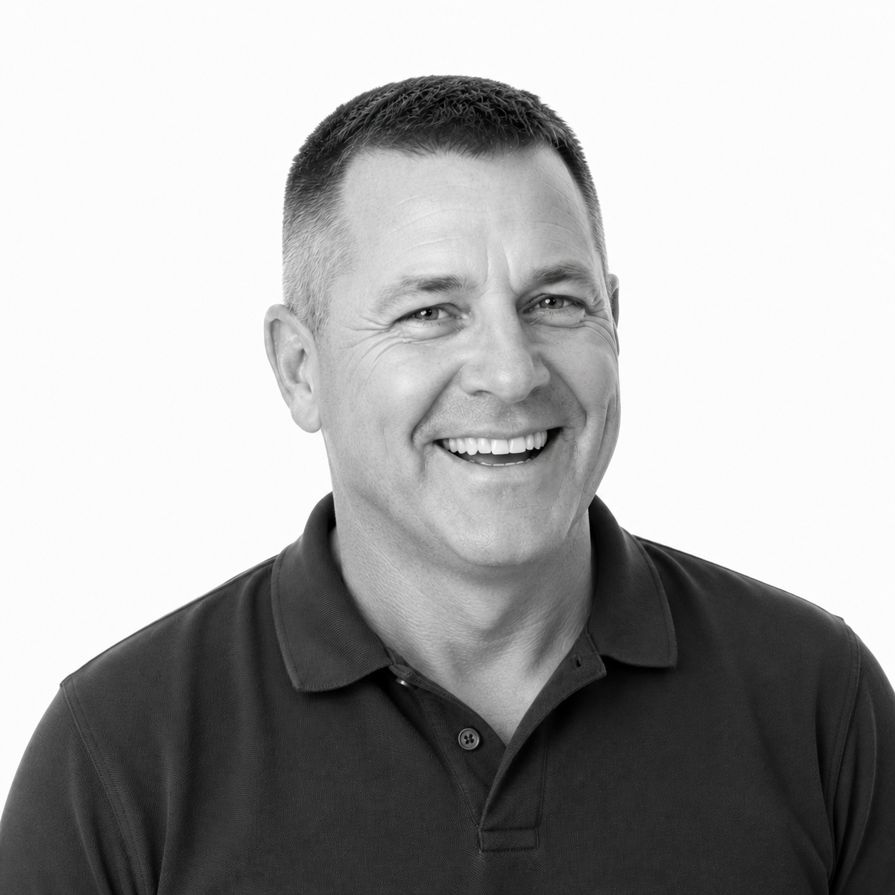 A black and white headshot of a smiling man with short dark hair, wearing a collared shirt.