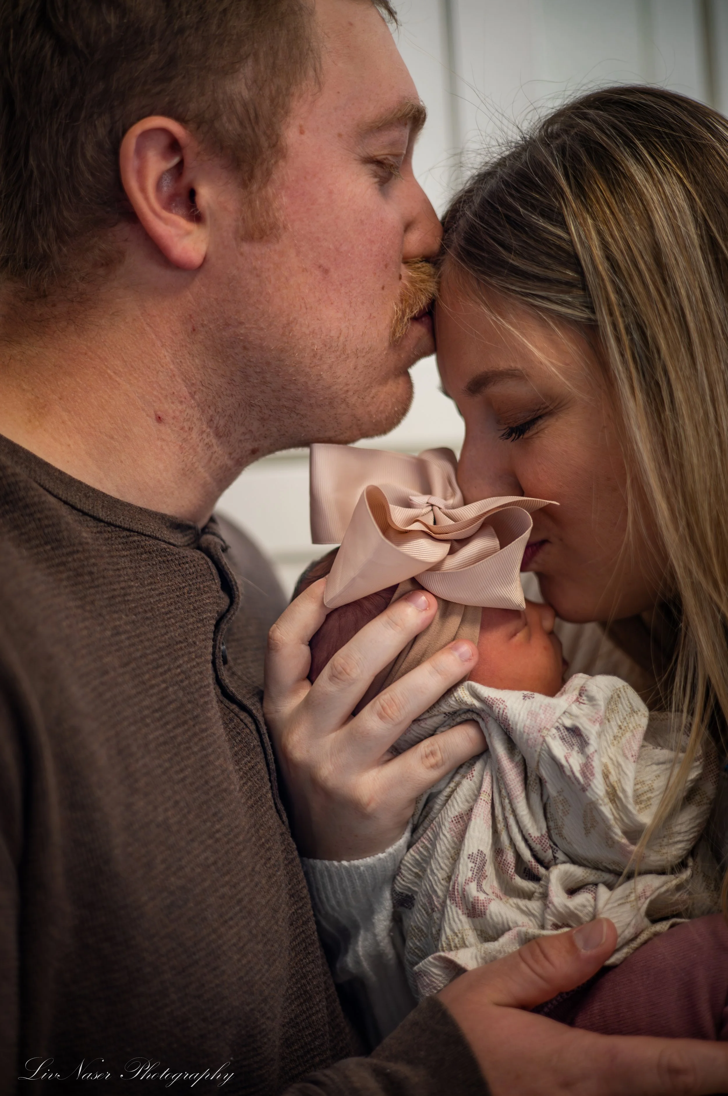 A man and woman share a tender moment as they gently touch foreheads, with the woman holding a small, wrapped gift.