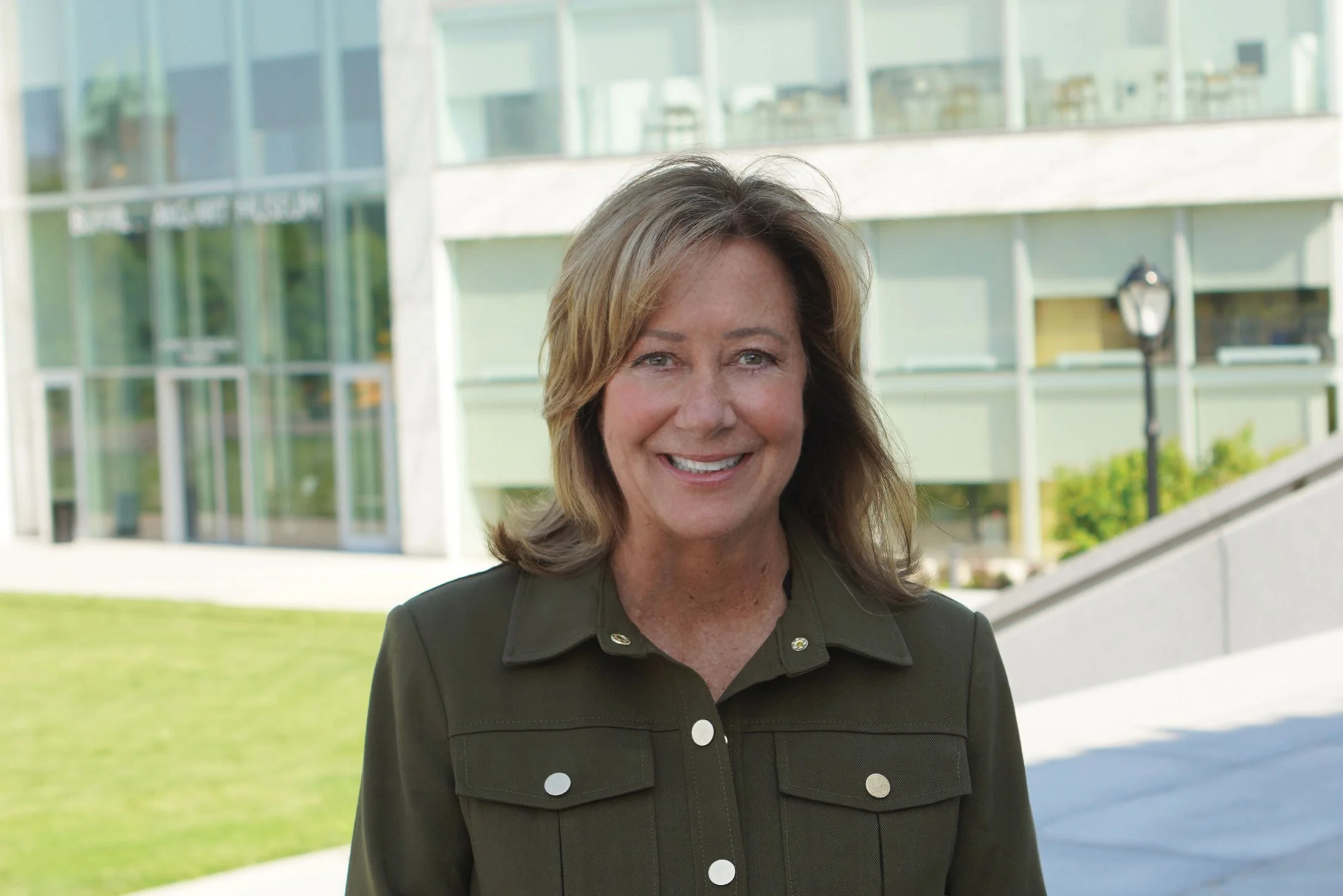 Roberta Bemiller standing in front of a modern glass building smiling.