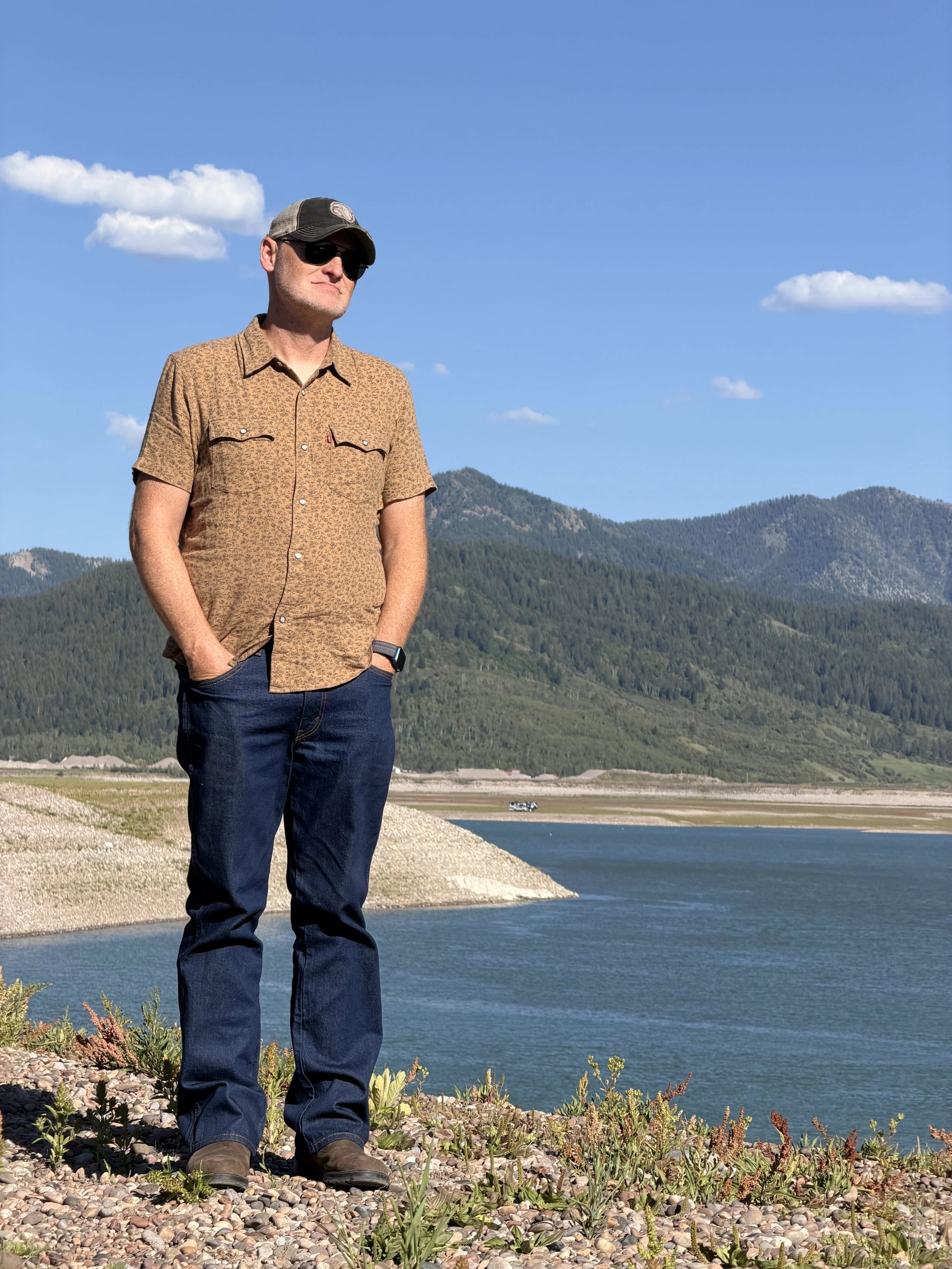 A man standing in front of a reservoir in the Wyoming mountains