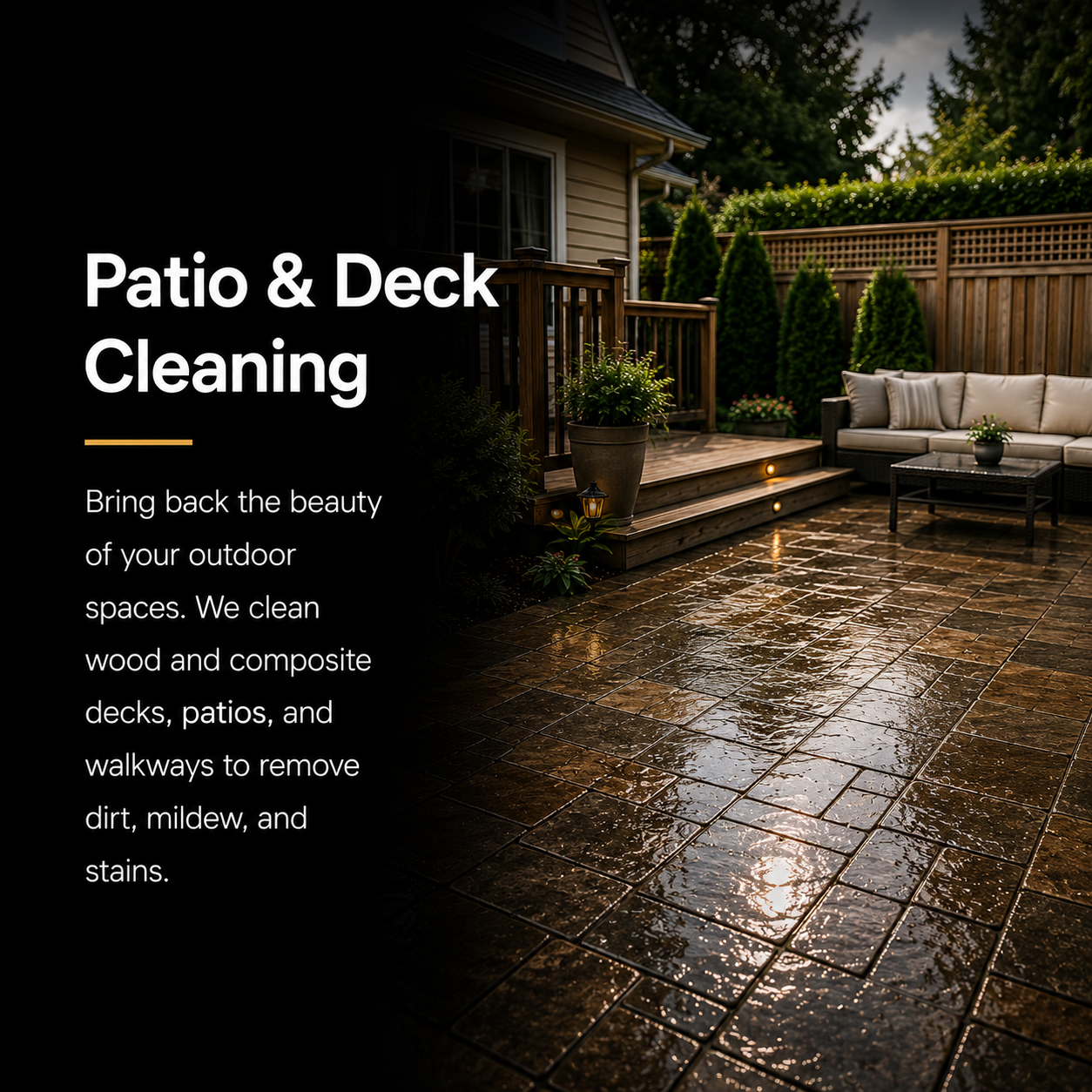 A backyard patio with wet, shiny brick flooring, a wooden deck with stairs, outdoor furniture including a beige sofa and a black table, surrounded by greenery and a wooden fence.