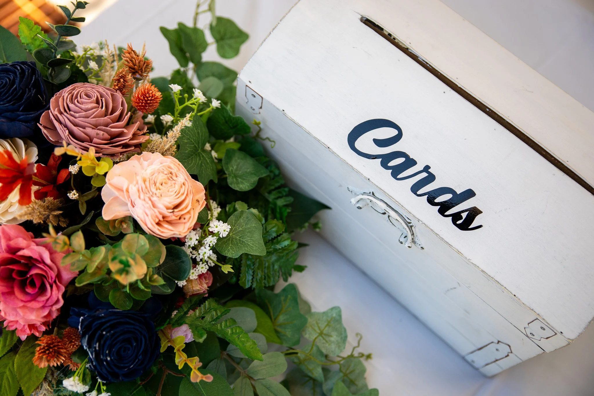 Colorful flowers including roses and greenery next to a white wooden box with the word 'laundry' written on it.