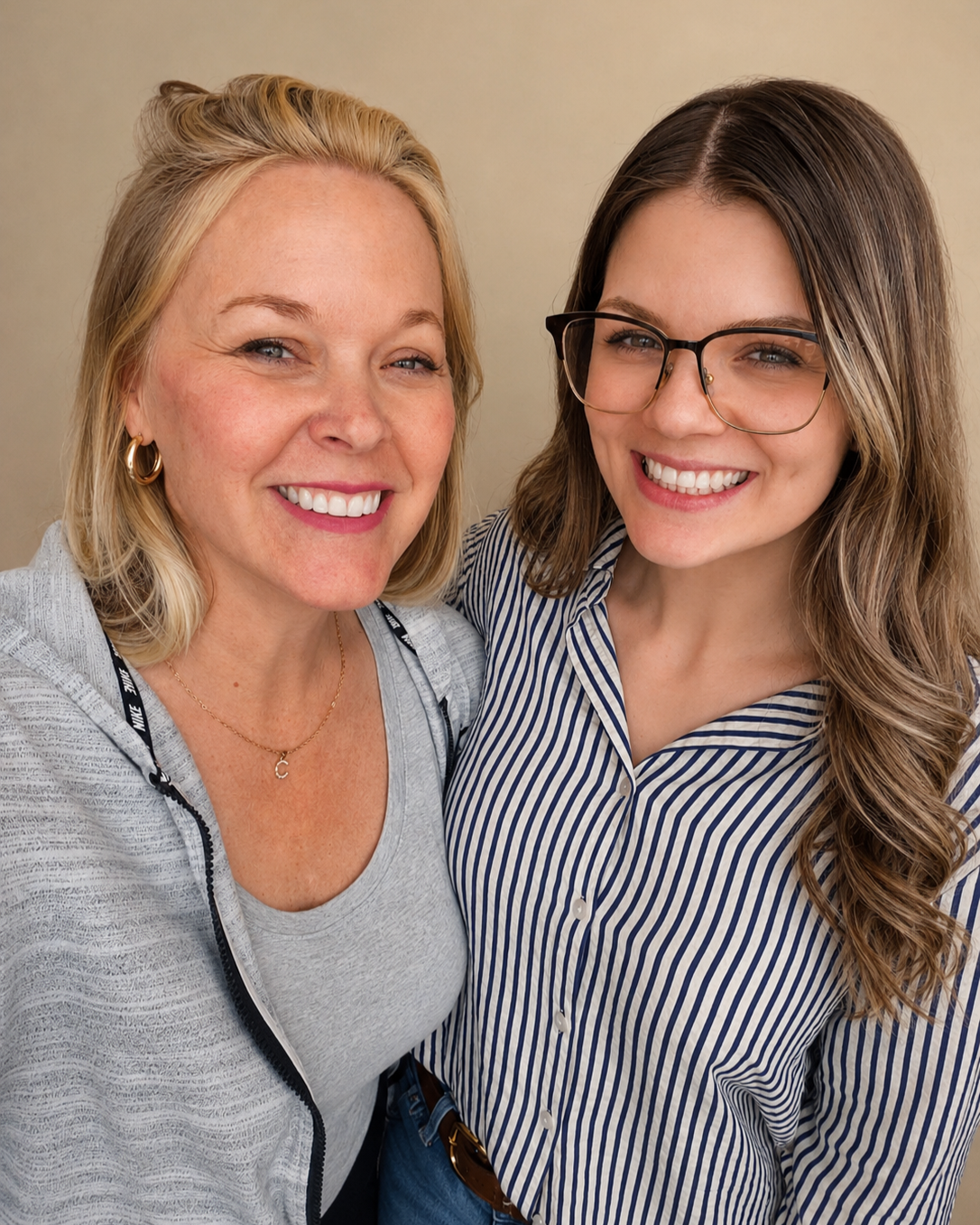 Two women smiling and taking a selfie together, one with blonde hair and the other with brown hair and glasses.
