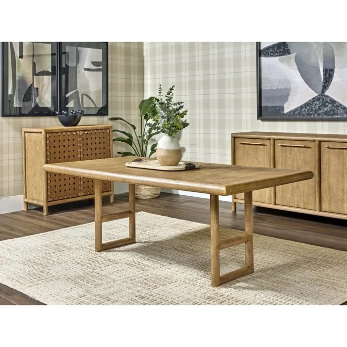 Sala de estar con mesa de madera, un mueble bajo con puertas, una planta en maceta y decoración moderna en las paredes