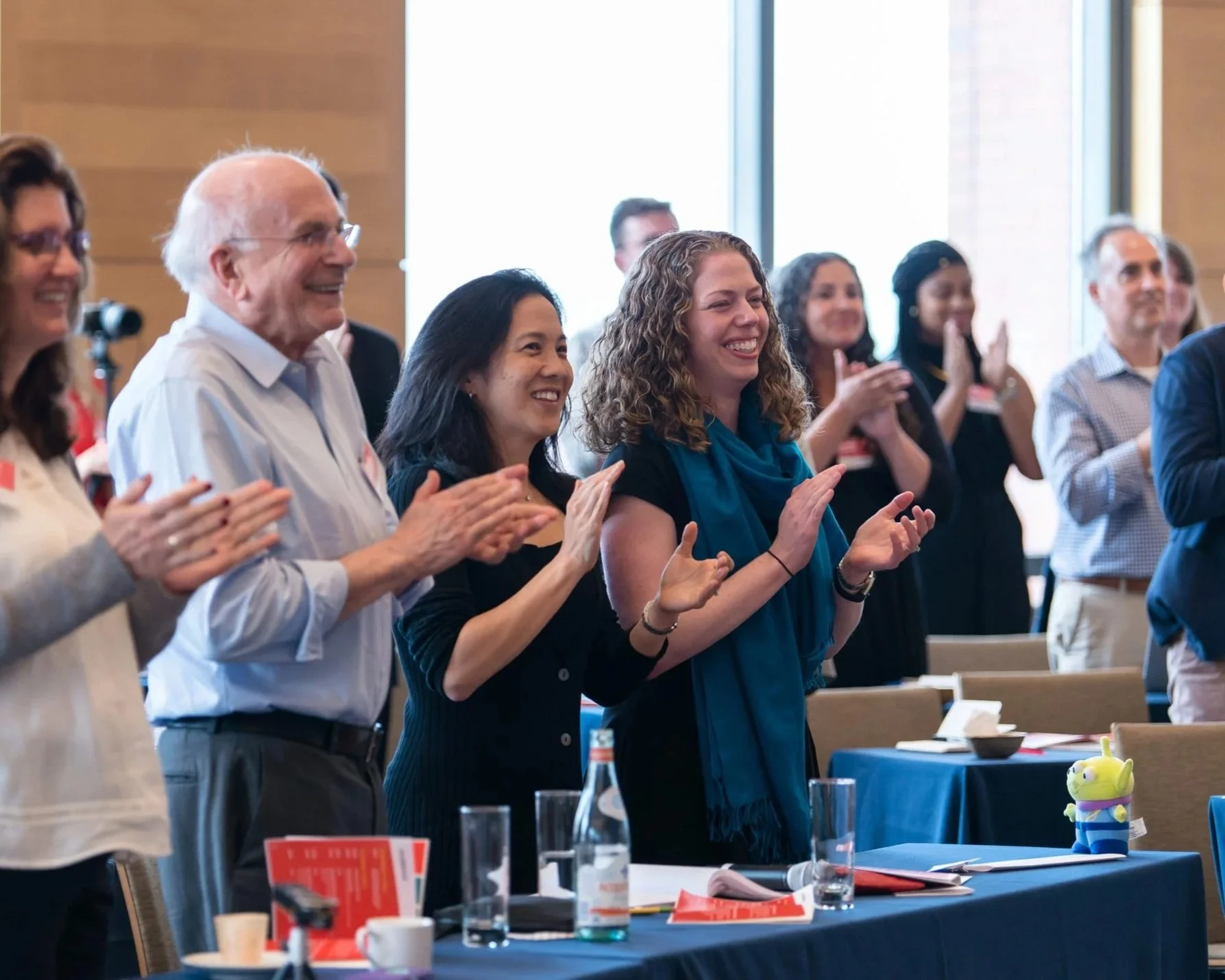 Group of diverse people standing and clapping in a conference room.