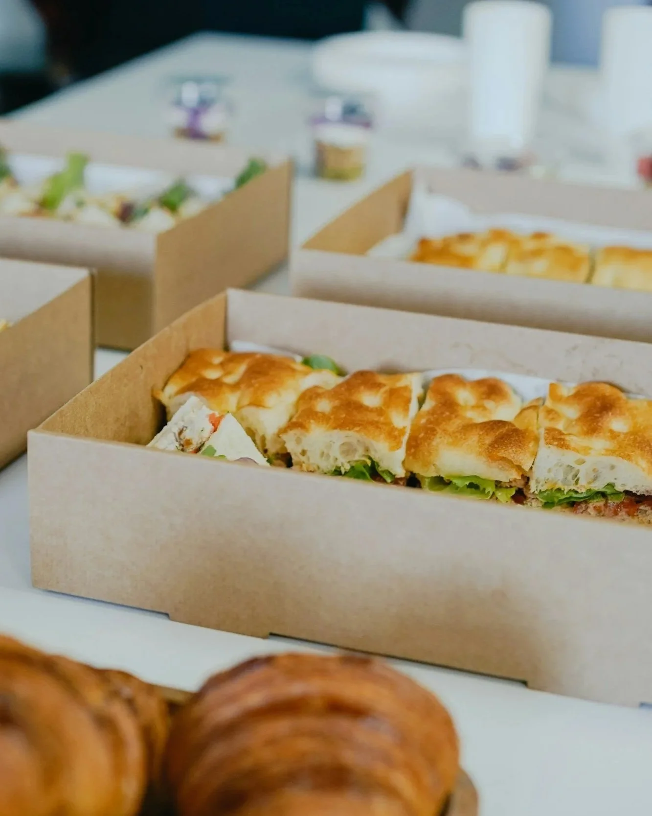 Boxes of assorted sandwiches and baked goods on a table.