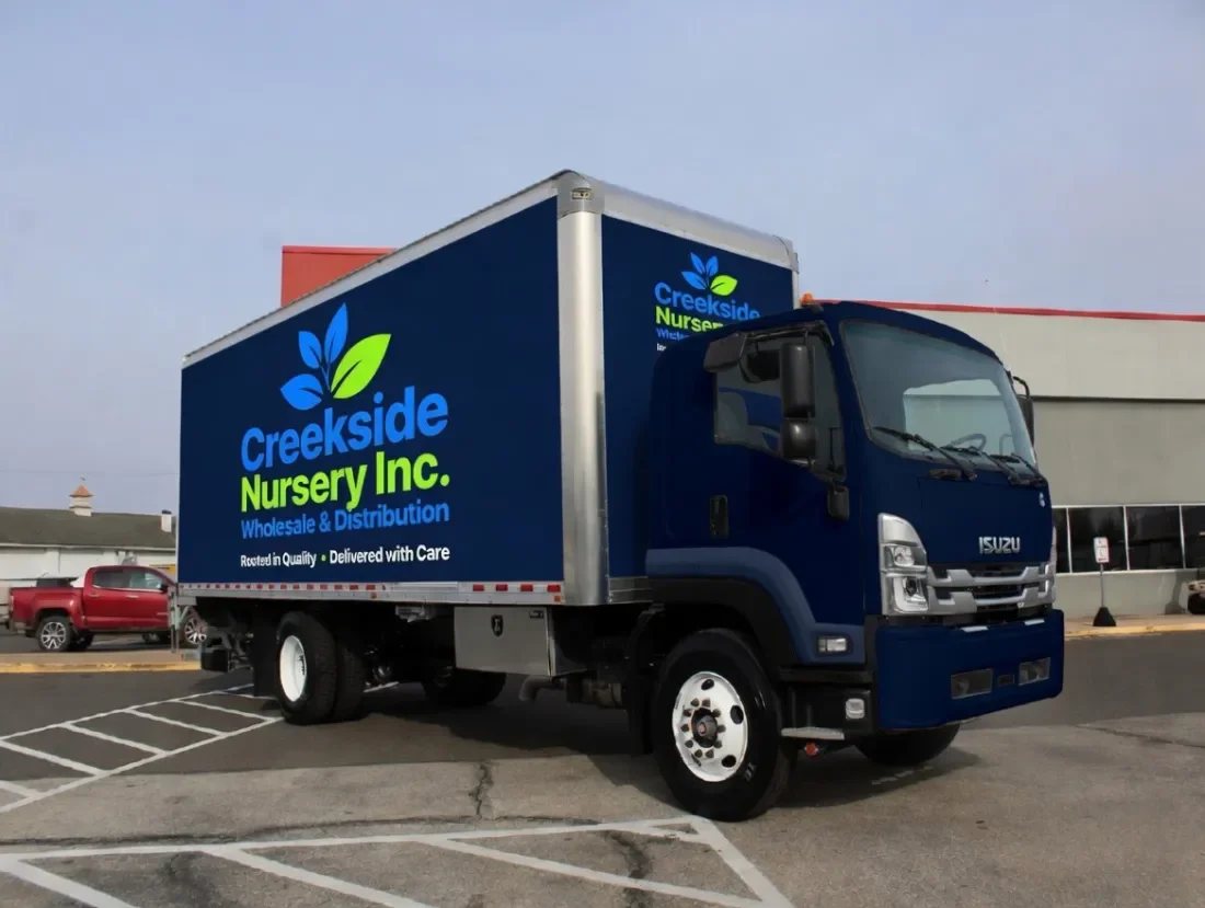A blue delivery truck with the logo and name of Creekside Nursery Inc. parked in a parking lot.