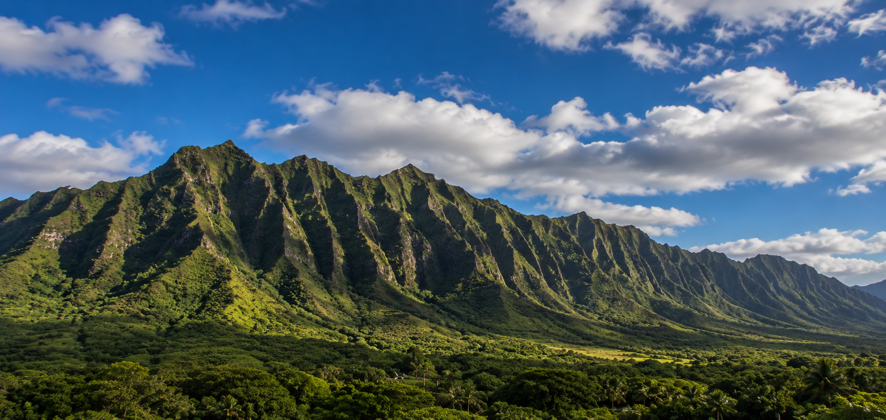 Lush green mountains under a partly cloudy sky.