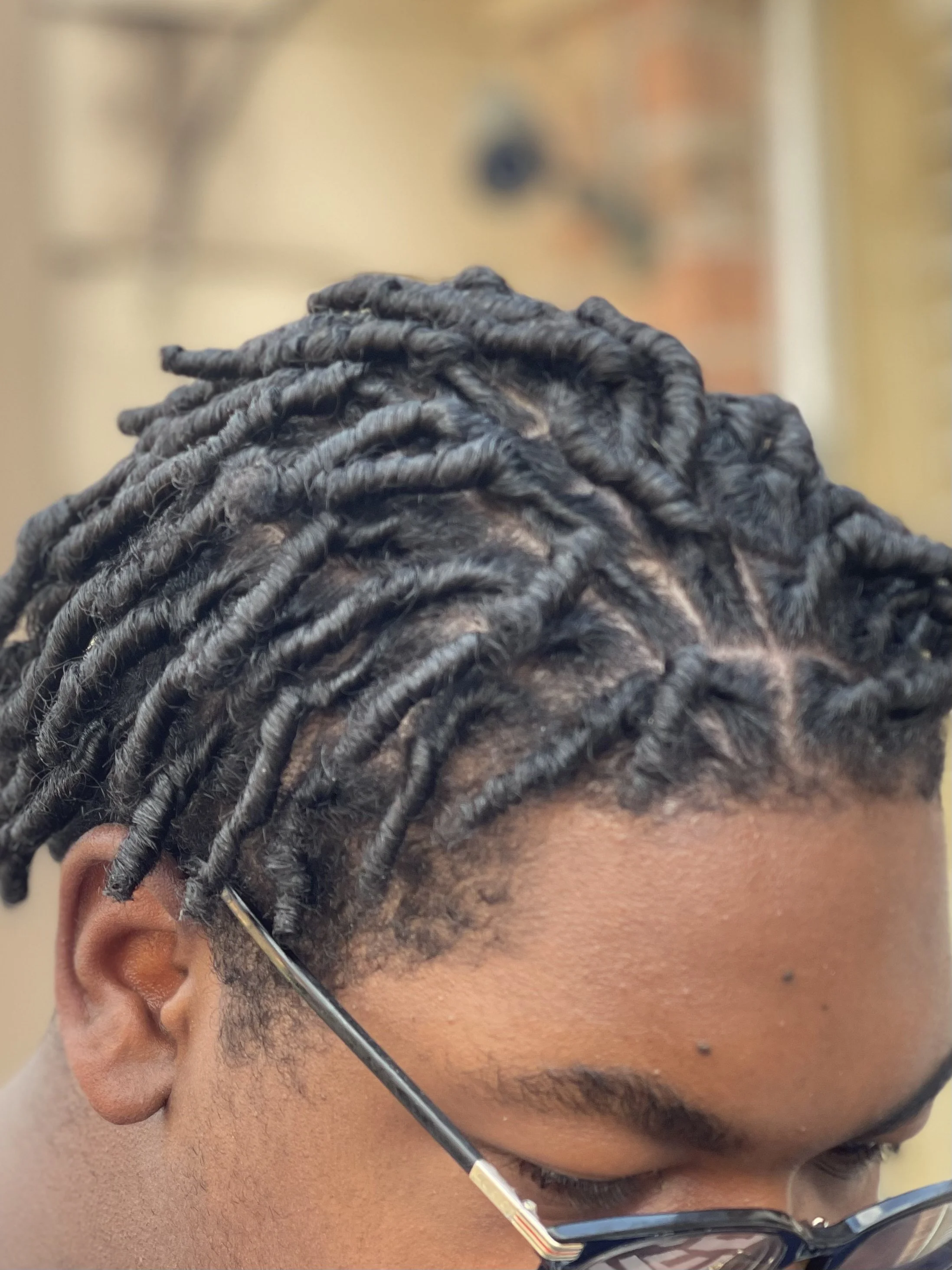 Close-up of starter loc comb coils on short natural hair.