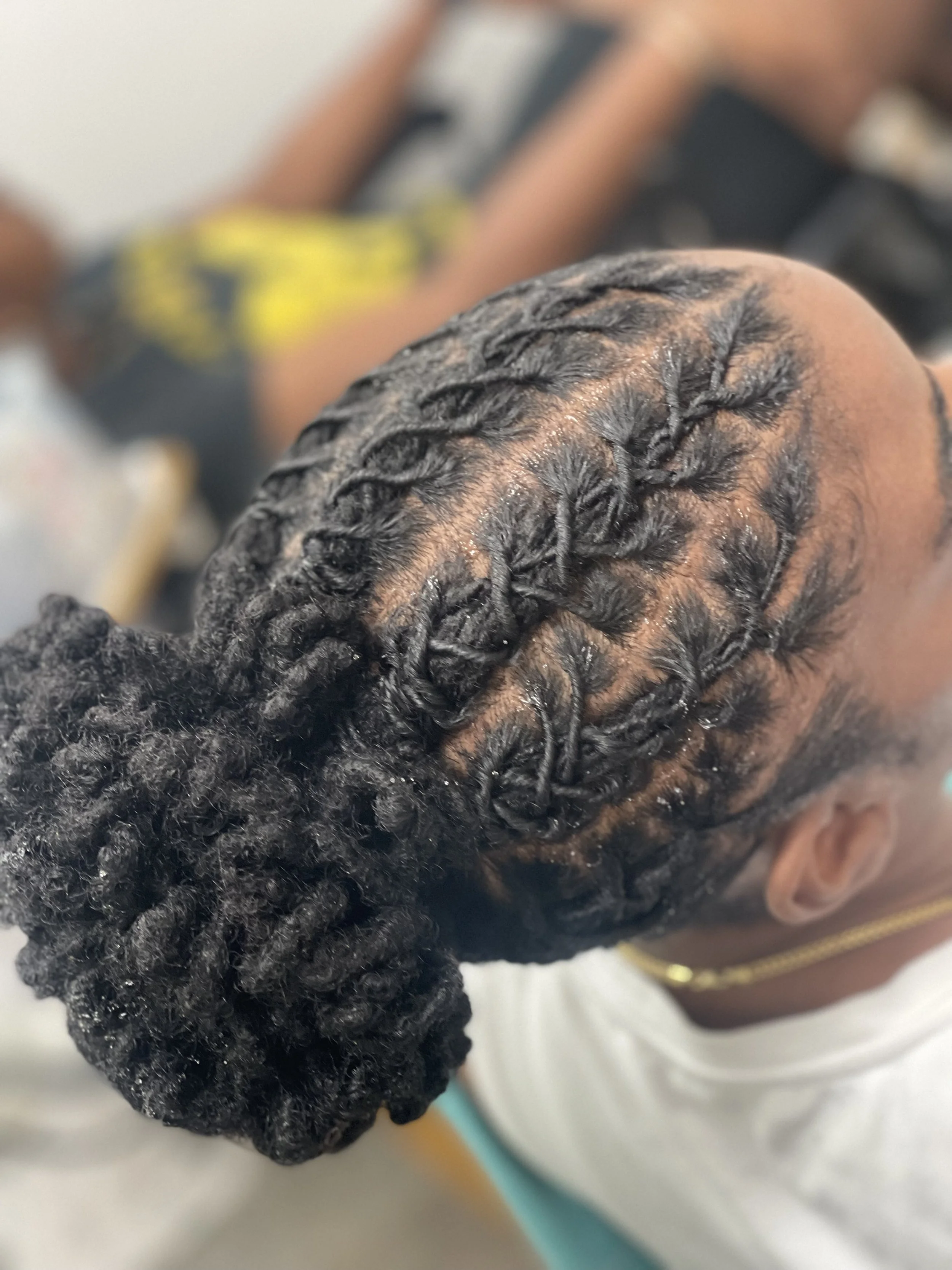 Close-up of a fresh retwist and updo loc style on long locs.