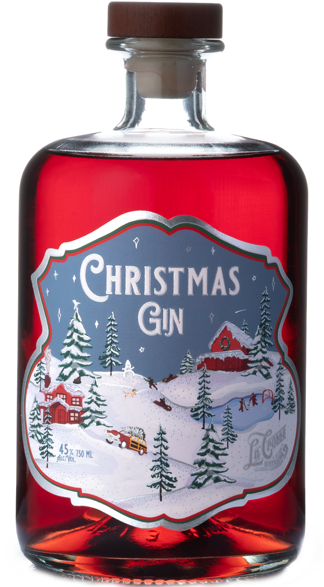 A bottle of Christmas-themed gin with a red label featuring a snowy winter scene, pine trees, a barn, and a car