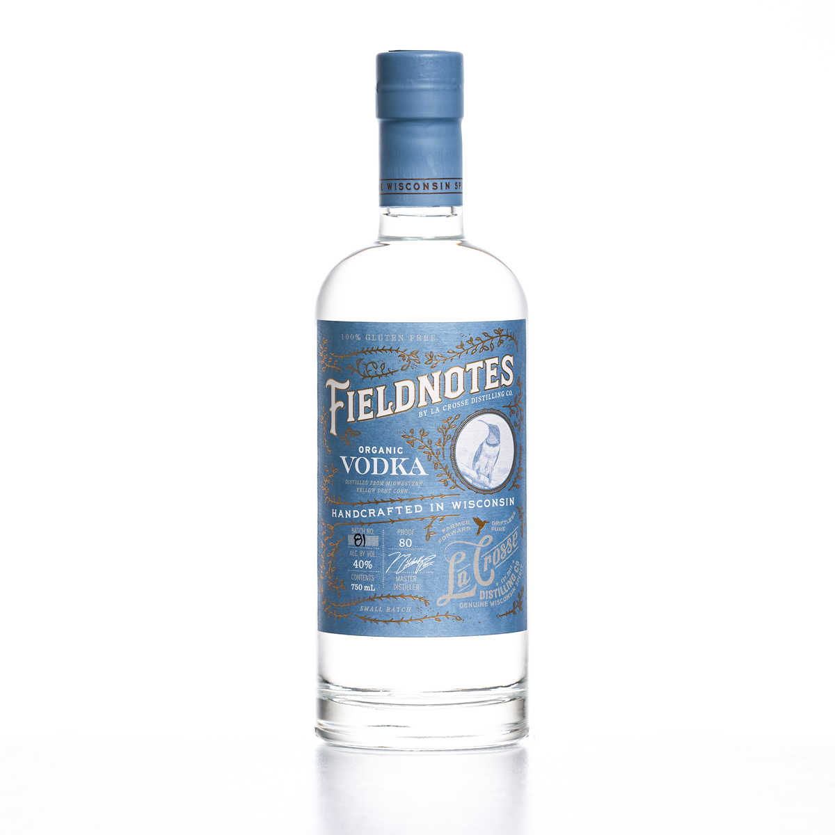 A clear glass bottle of Fieldnotes organic vodka with a blue label and cap, featuring white and gold text, logo, and decorative elements.