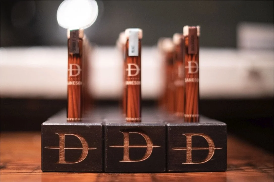 Close-up of several chocolate bars with the letter D on the packaging, arranged in a row on a wooden surface.