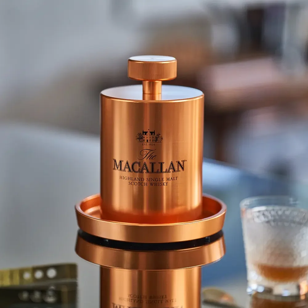 A photograph of a copper colored Macallan ice press on a bar top