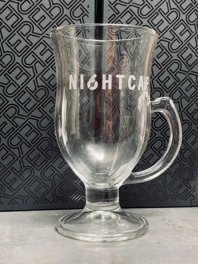 A hot toddy glass engraved with the word "NIGHTCAP" but with the G replaced by 6sense's logo of the number 6