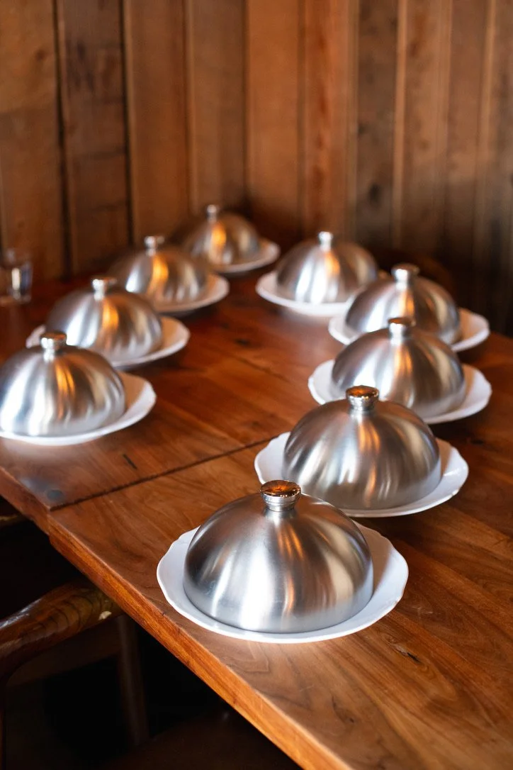 A photo of stainless steel cloches hiding a surprise dessert