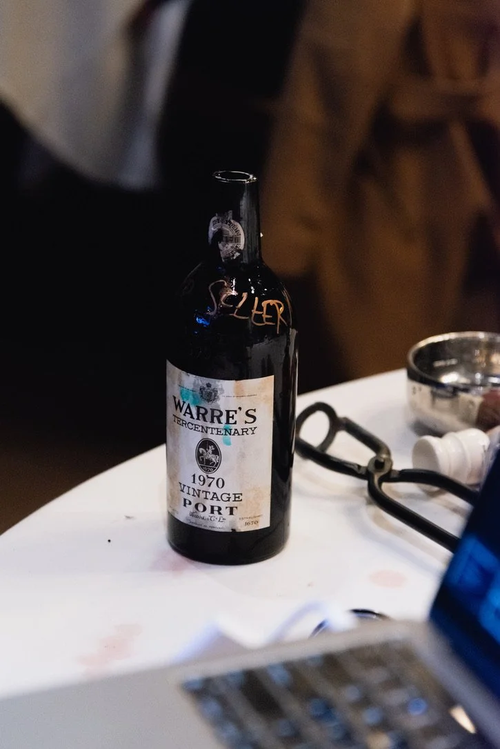 A dark glass bottle of Warre's 1970 vintage port wine after it has been successfully tonged at the 6sensory Supper in San Francisco in early 2023.
