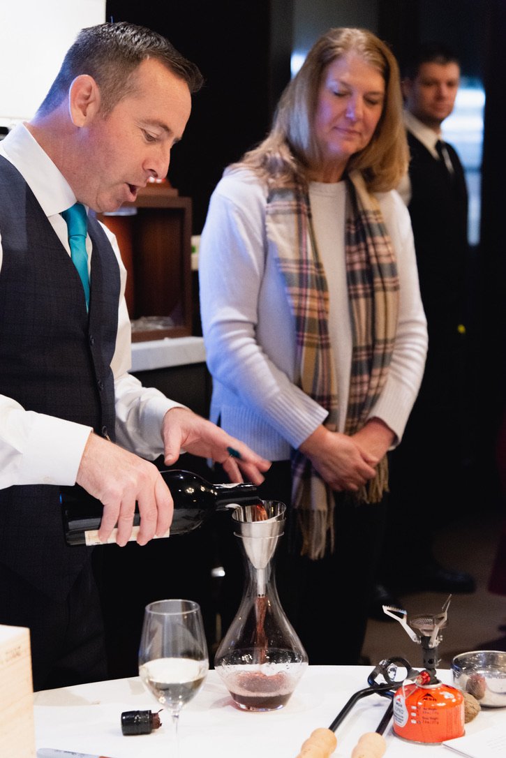 A handsome gentleman is decanting a vintage bottle of Port after using Port tongs to open it