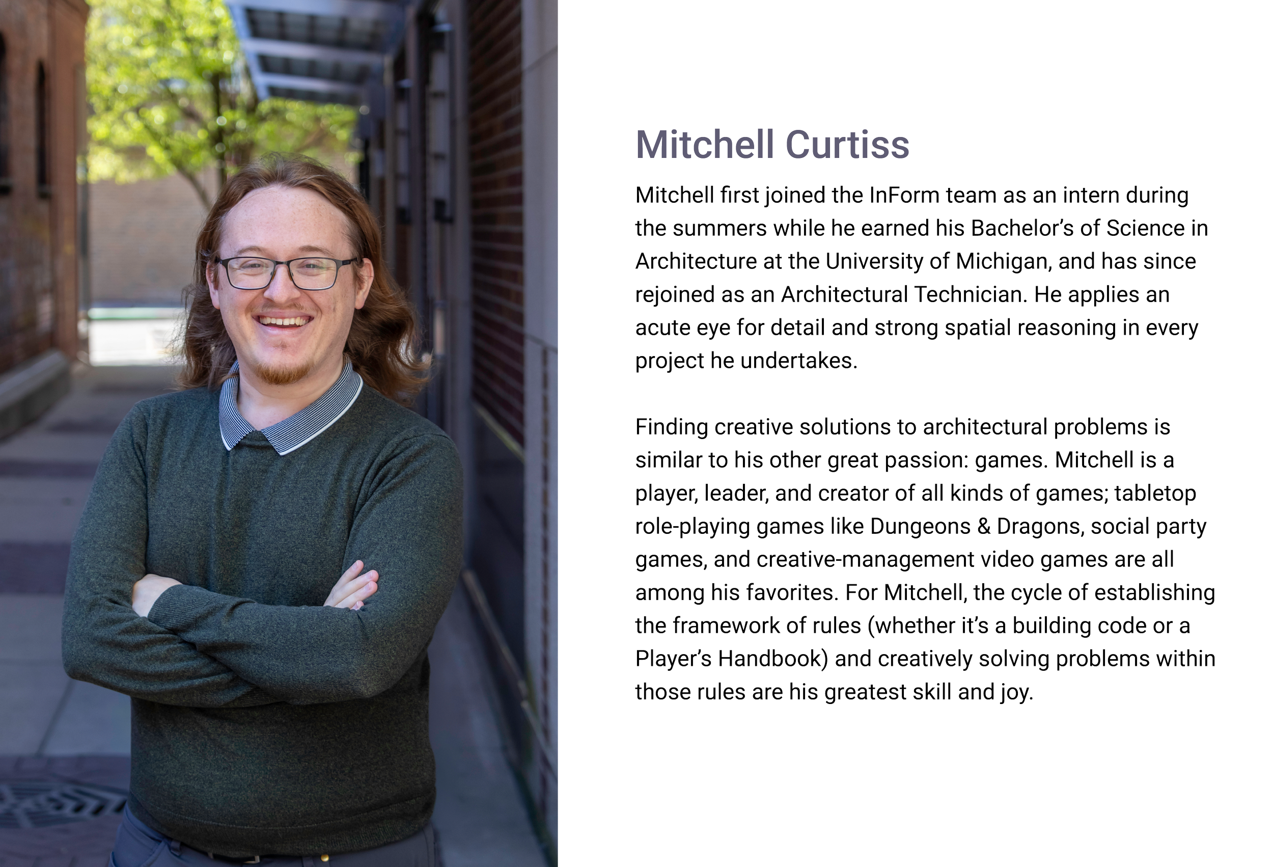 Mitchell Curtiss, Architectural Designer of E.H. Goodman Architects. young man with shoulder-length red hair, glasses, and a goatee, smiling with arms crossed, standing outdoors near a brick building with greenery in the background.