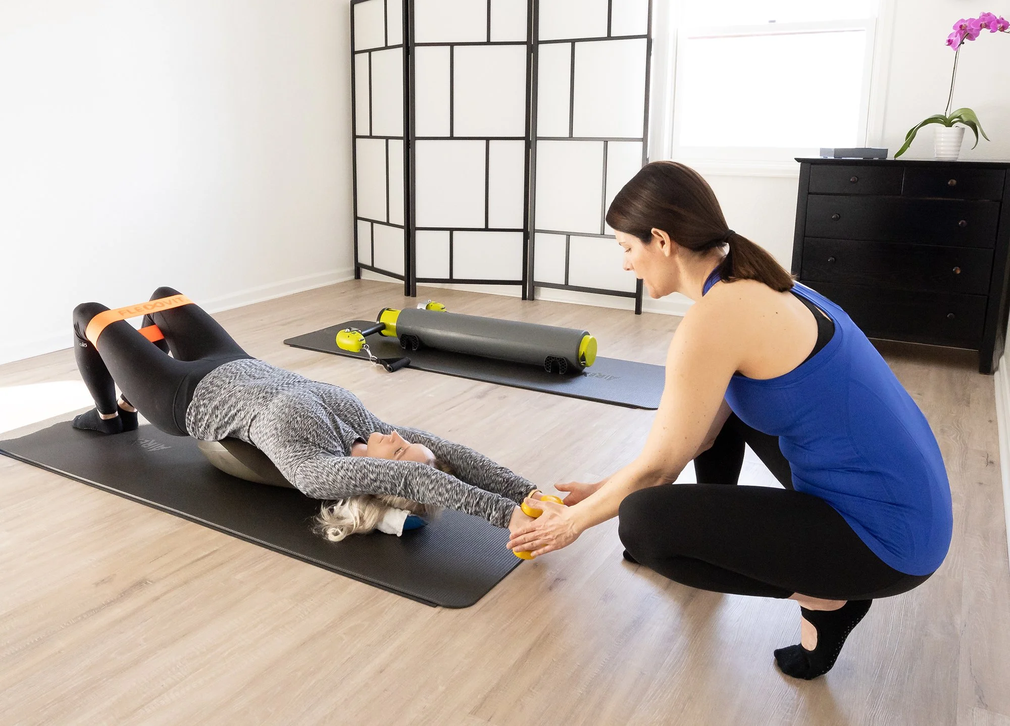 A Taylor Pilates & Fitness movement practitioner working in a private session with the Oov, a unique apparatus designed to mimic the natural curves of the spine, and pilates bands.