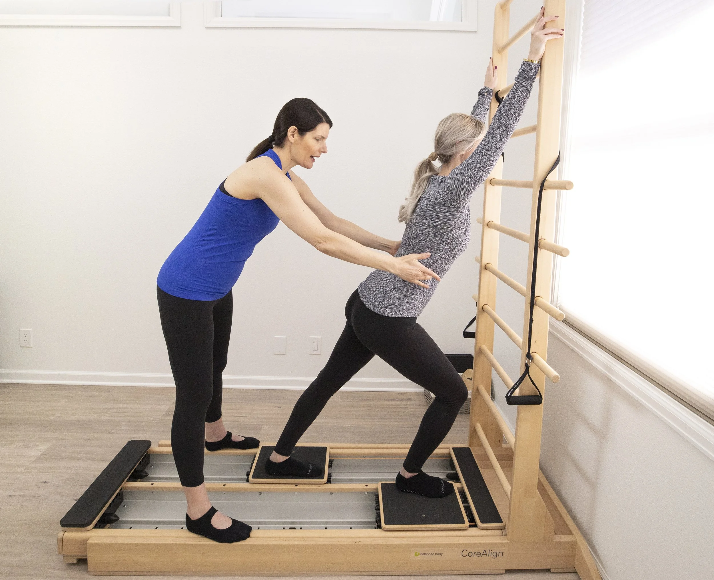 A Taylor Pilates & Fitness movement practitioner working with a client during a private pilates mat session utilizing the CoreAlign, an exercise and rehabilitation device with moving foot carts on smooth tracks.