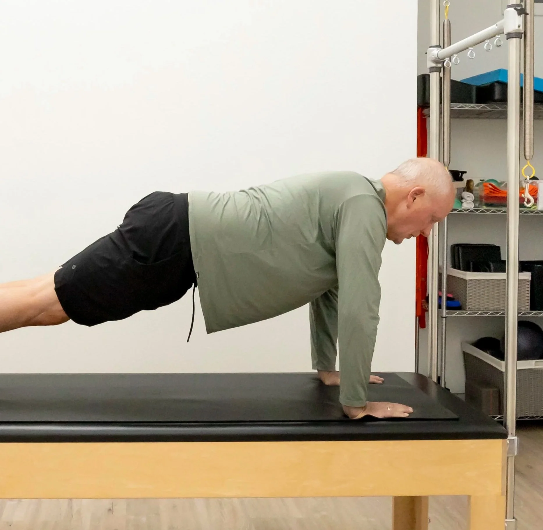 A Taylor Pilates & Fitness movement practitioner working with a senior client to build strength and balance during a private pilates session on the Pilates trapeze table.