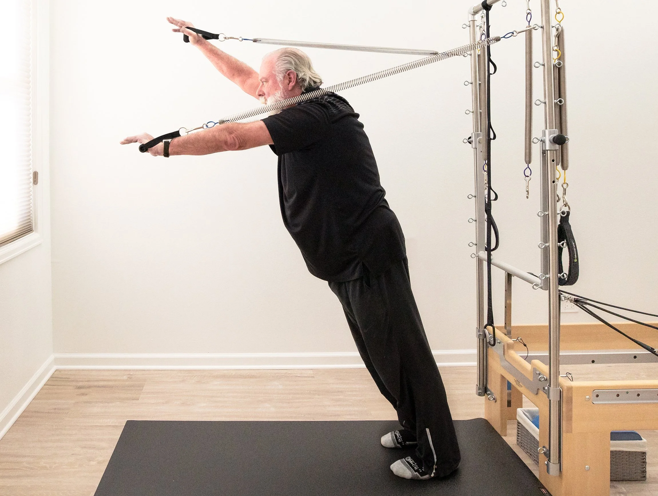 A Taylor Pilates & Fitness senior client, working to build strength and balance during a private pilates session on the Pilates Reformer.