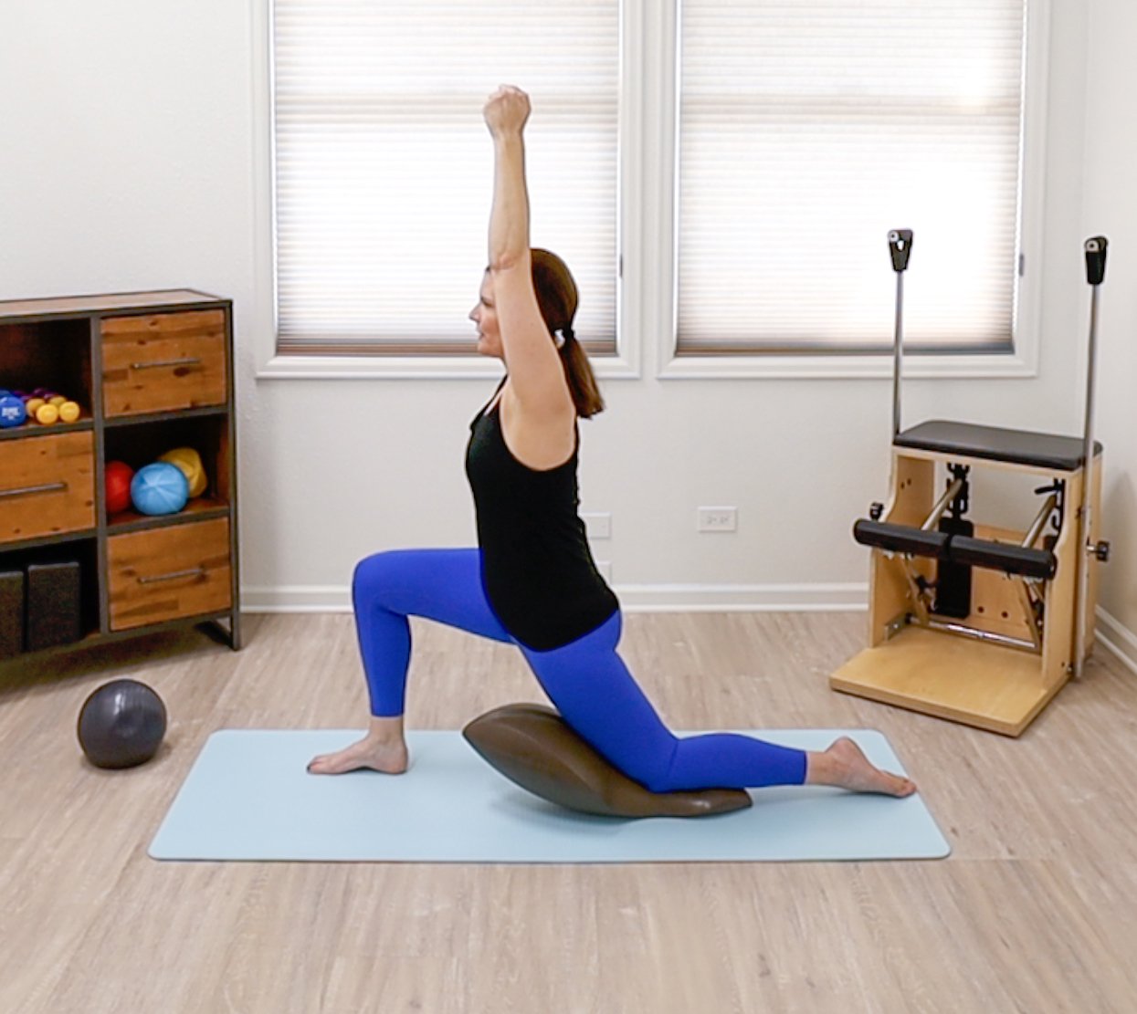 An image from one of the Taylor Pilates & Fitness online Oov classes showing how to utilize the Oov - a unique apparatus designed to mimic the natural curves of the spine.