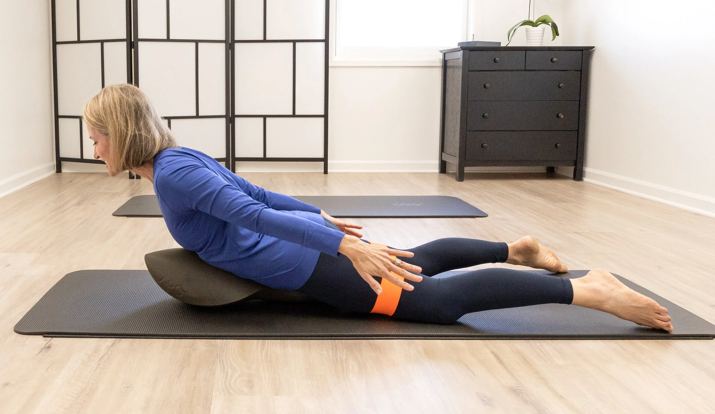 A Taylor Pilates & Fitness movement practitioner working with a client during a private pilates mat session utilizing the Oov, a unique apparatus designed to mimic the natural curves of the spine.