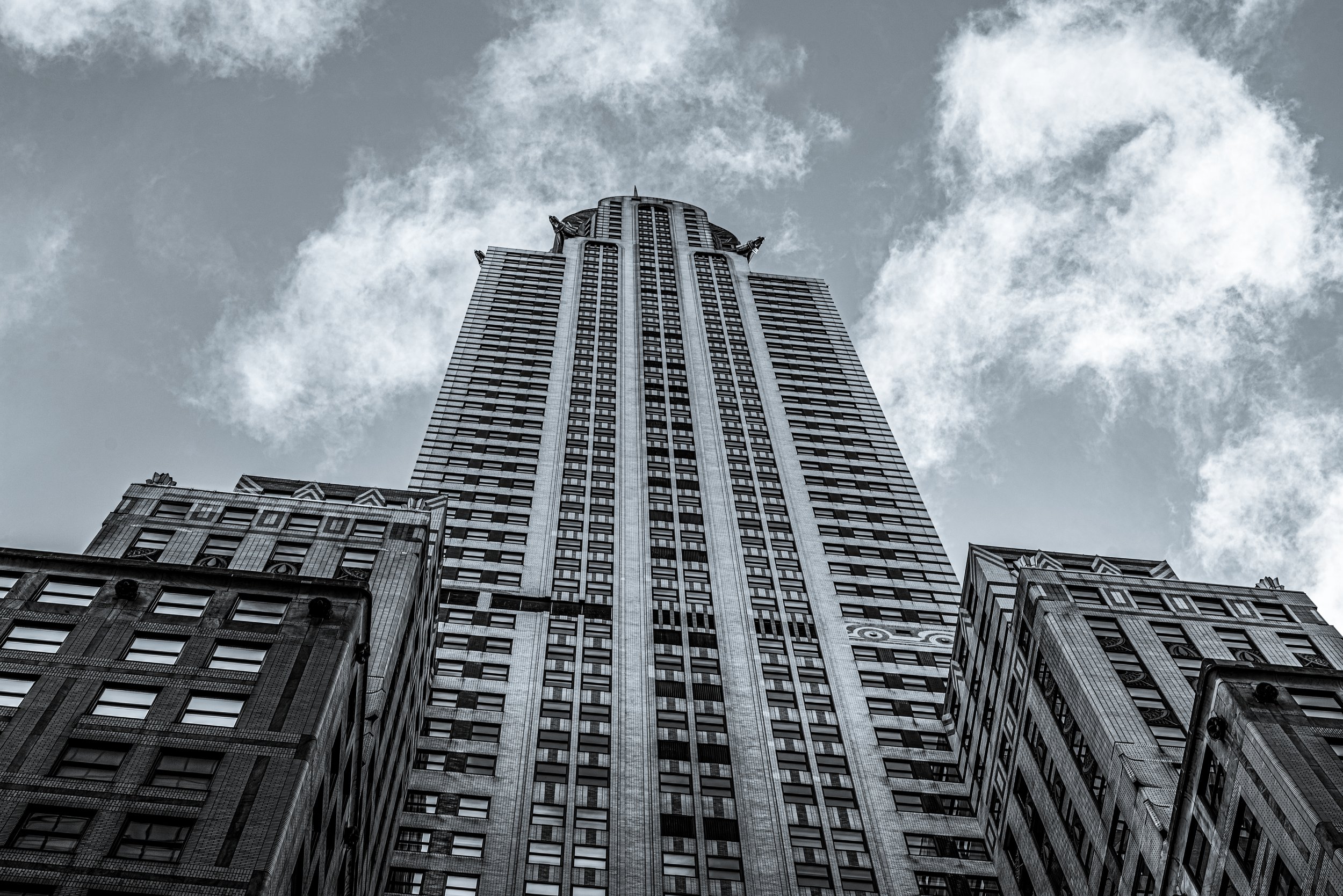 A tall skyscraper viewed from the ground looking up, with a cloudy sky in the background.