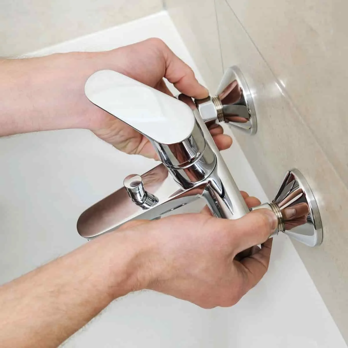 two hand holding a faucet during a plumbing fixture replacement