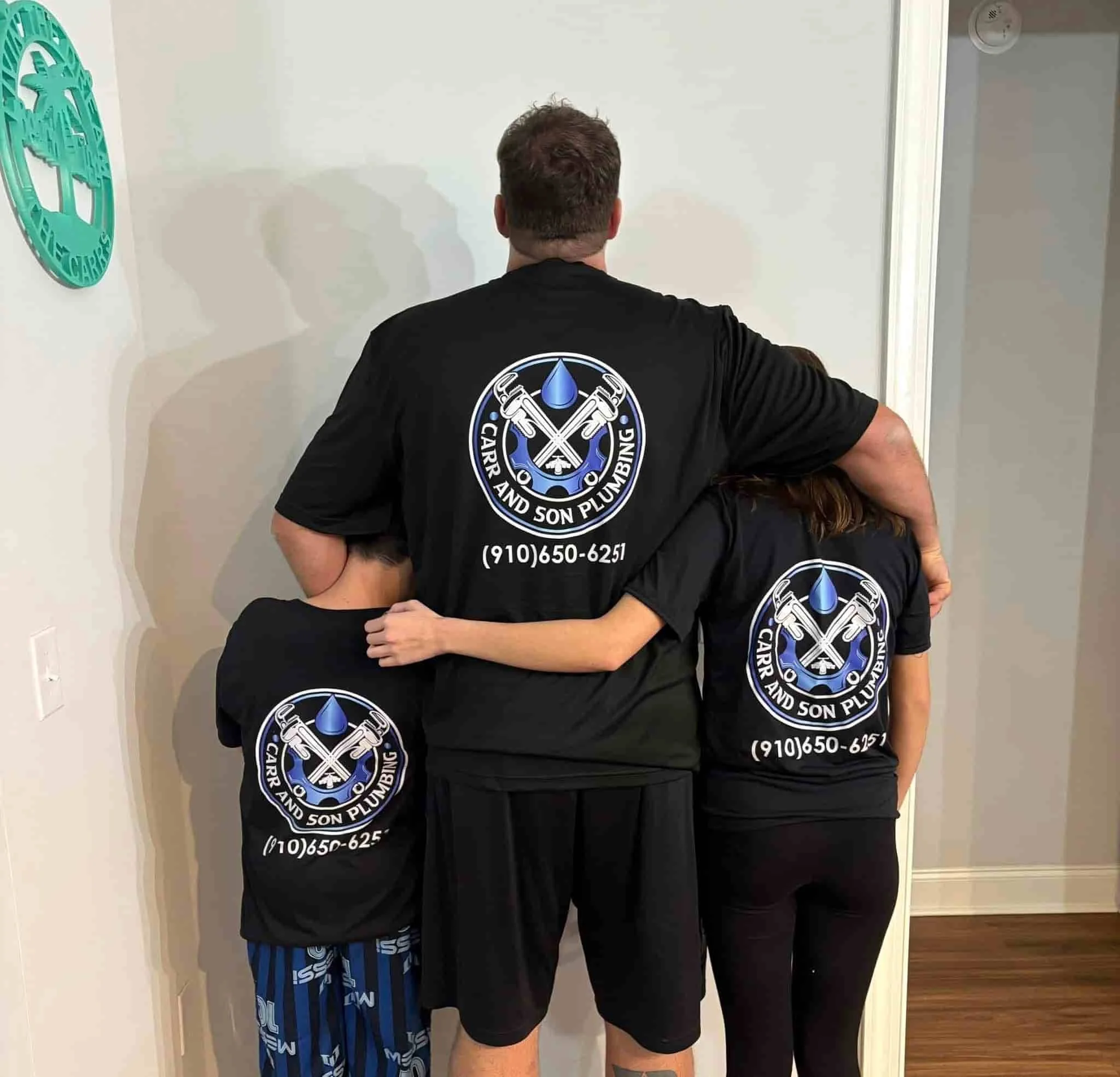 Three people wearing Carr and Son Plumbing t-shirs