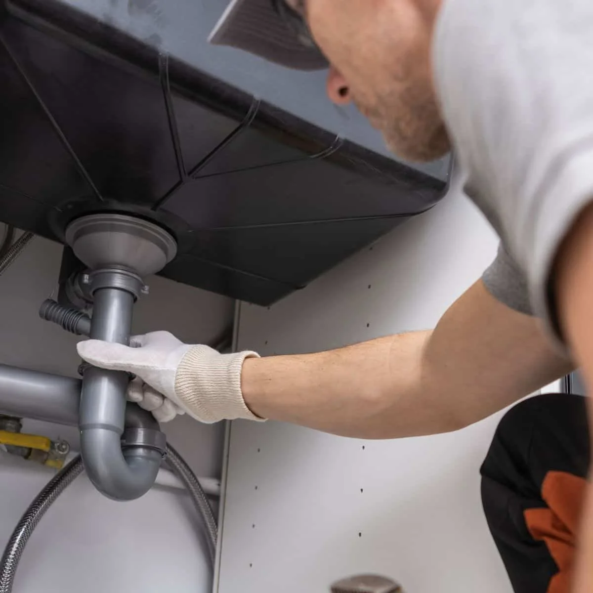 a man wearing gloves grabbing a pipe and inspecting if for maintenance