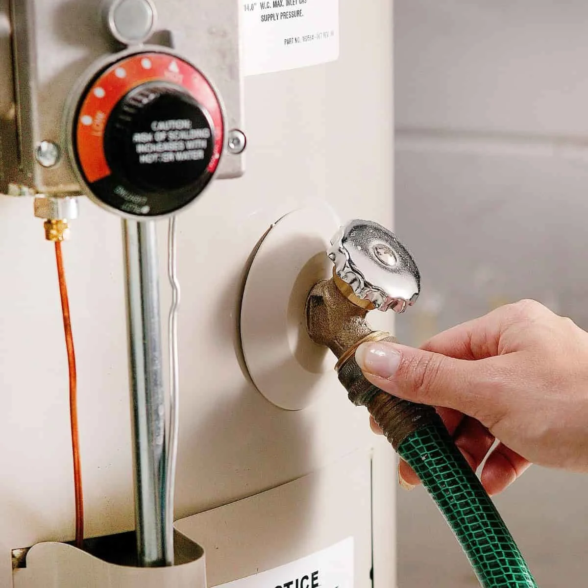 a hand connecting a hose to a water heater