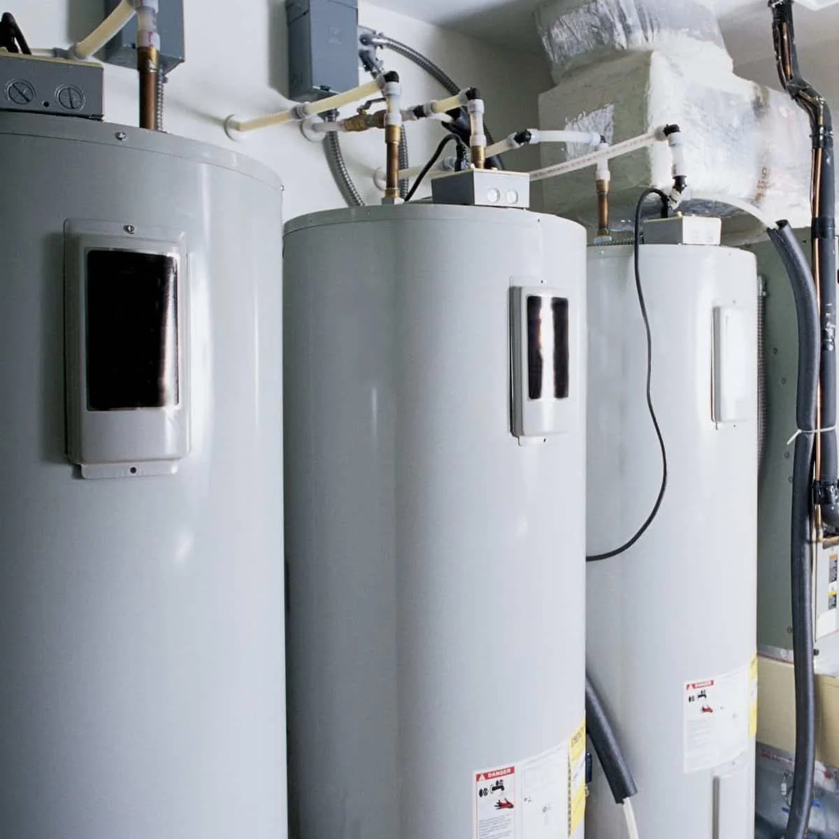 three water heaters next to each other along a wall in a commercial building