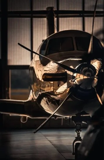 Front view of a shiny, black private airplane parked inside a hangar.