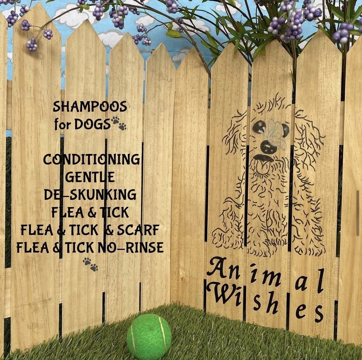 A wooden fence with a drawing of a dog and text promoting pet grooming and care services. The background has a blue sky with clouds and a purple flowering plant. A yellow tennis ball sits on green grass in front of the fence.