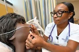 Nursing student administering a nasal cannula to a sim lab manikin.