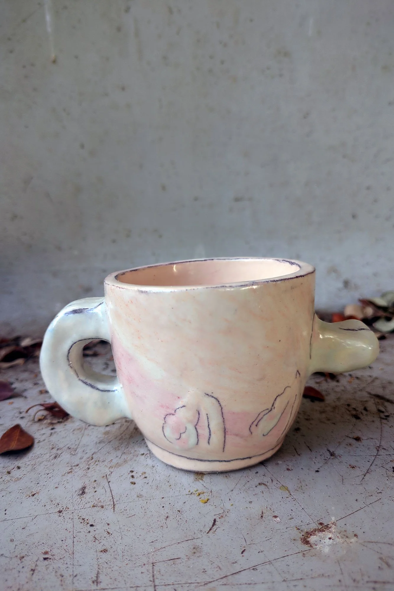 jJohanna Jackson ceramic cup back view showing two young plants pushing from earth, pencil lines on pale pink porcelain