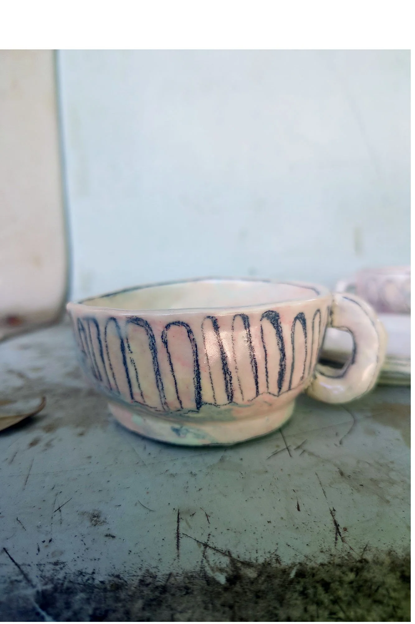Large porcelain cup with handle on right, expressive arch motifs in graphite and blue