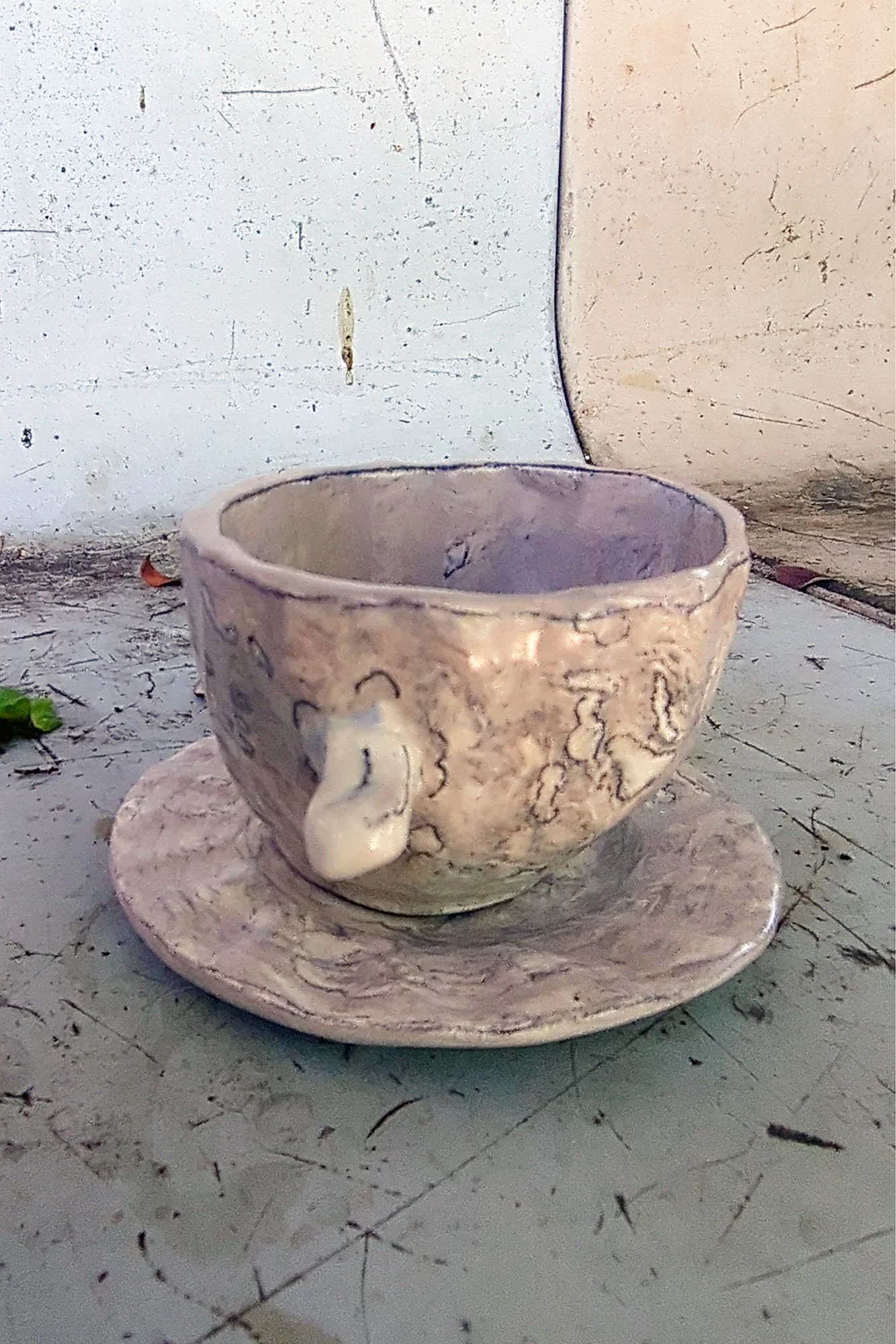 Front view of hand-built marbled porcelain cup and saucer, little nub handle, pencil line details