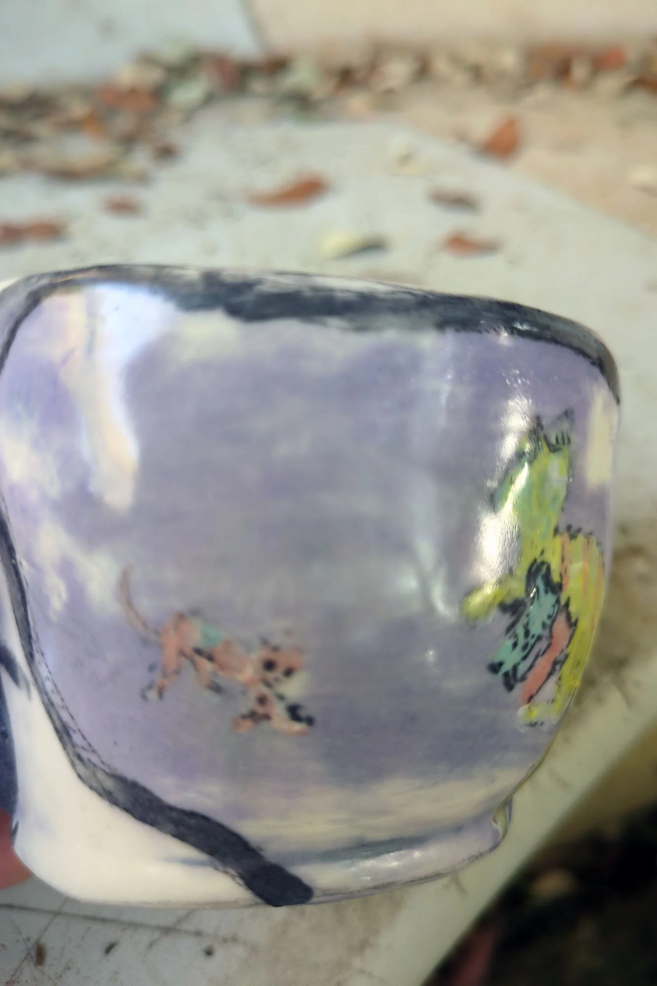 Close detail of painted detail of errant kitten on lavender porcelain cup, expressive soft glaze