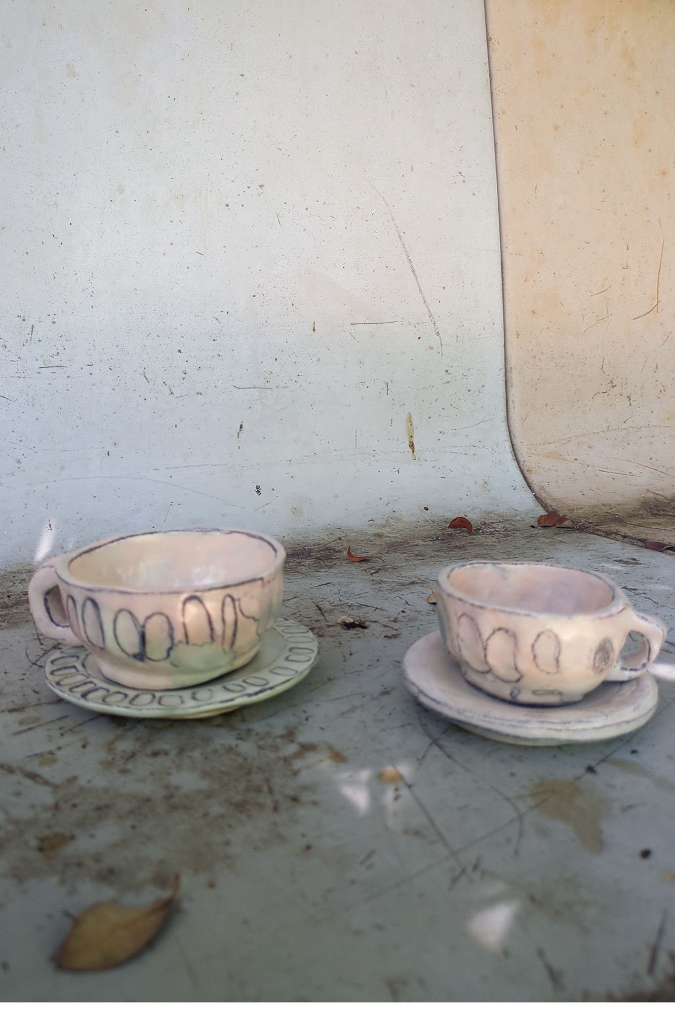 Pair of expressive studio porcelain cups on saucers, angled view, soft glaze