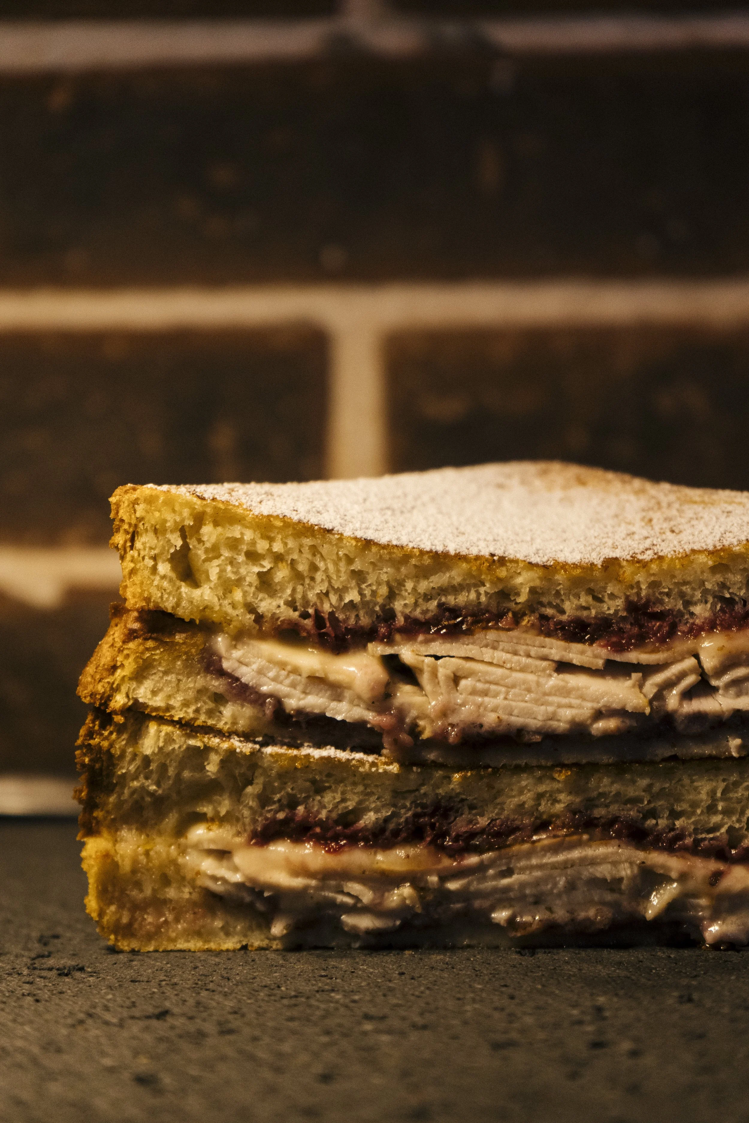 Clásico sándwich Monte Cristo con pavo, queso suizo, mostaza rústica, mermelada de moras y mayo de miso en pan de masa madre, dorado en mezcla de huevo y espolvoreado con azúcar glass de Comma - Sandwich Social Club, zona 14 Ciudad de Guatemala.