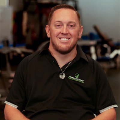 Hal Hargrave with short hair and a goatee smiling at the camera in a black shirt with a logo, sitting in an indoor setting.