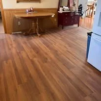Wooden floor in a kitchen with a dining table and chairs in the background.