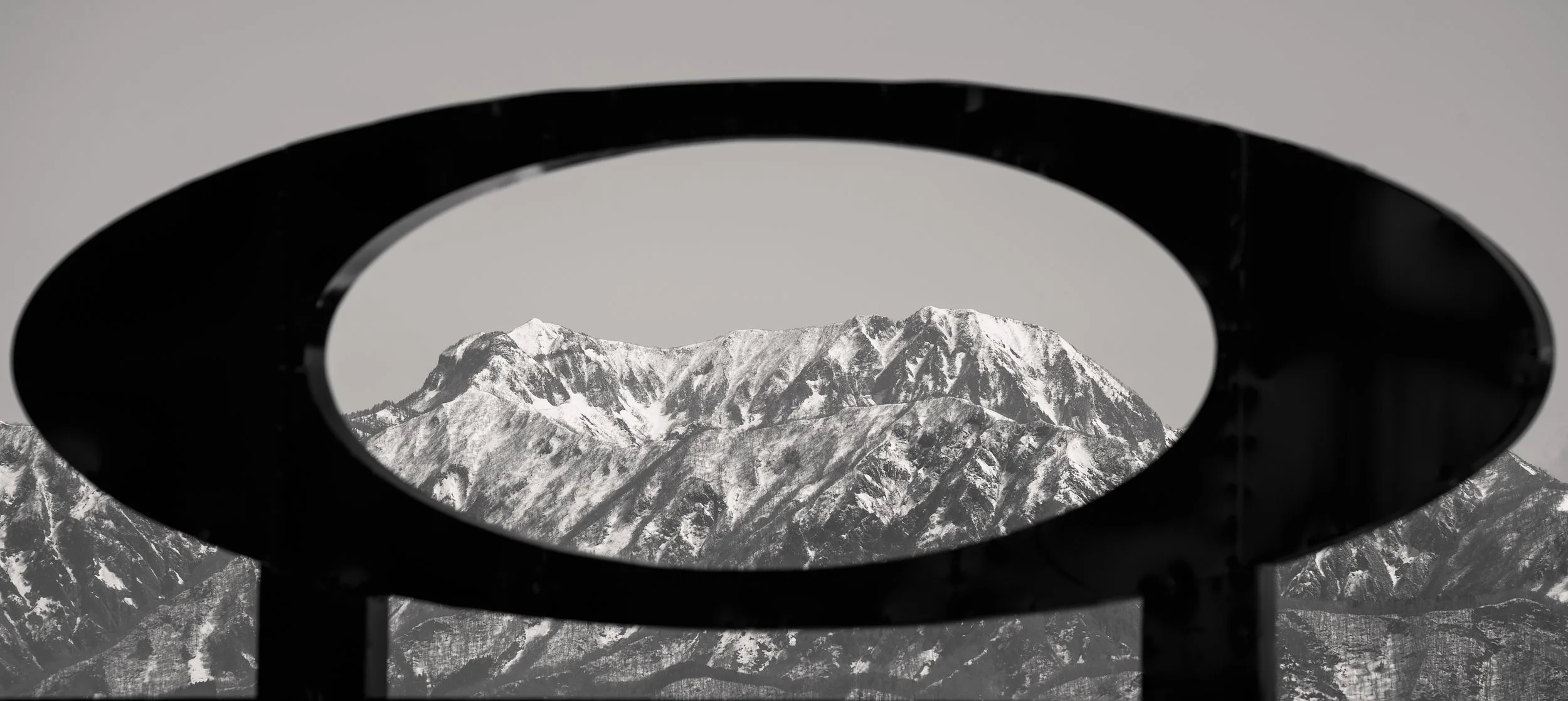 Snow-covered mountains viewed through a circular frame.